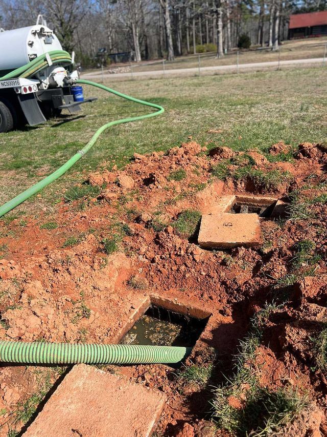 A septic tank is being filled with water by a vacuum truck.