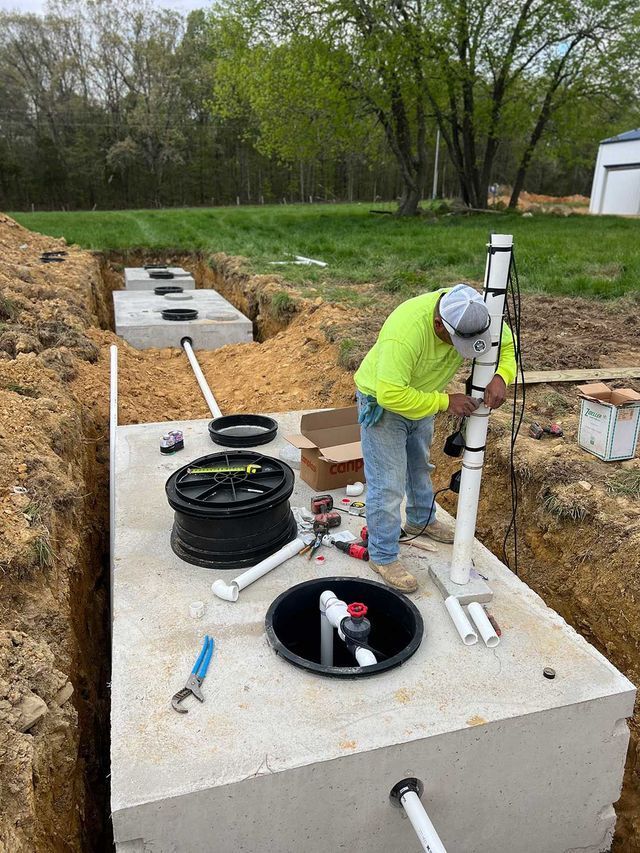 A man is working on a septic tank in the dirt.