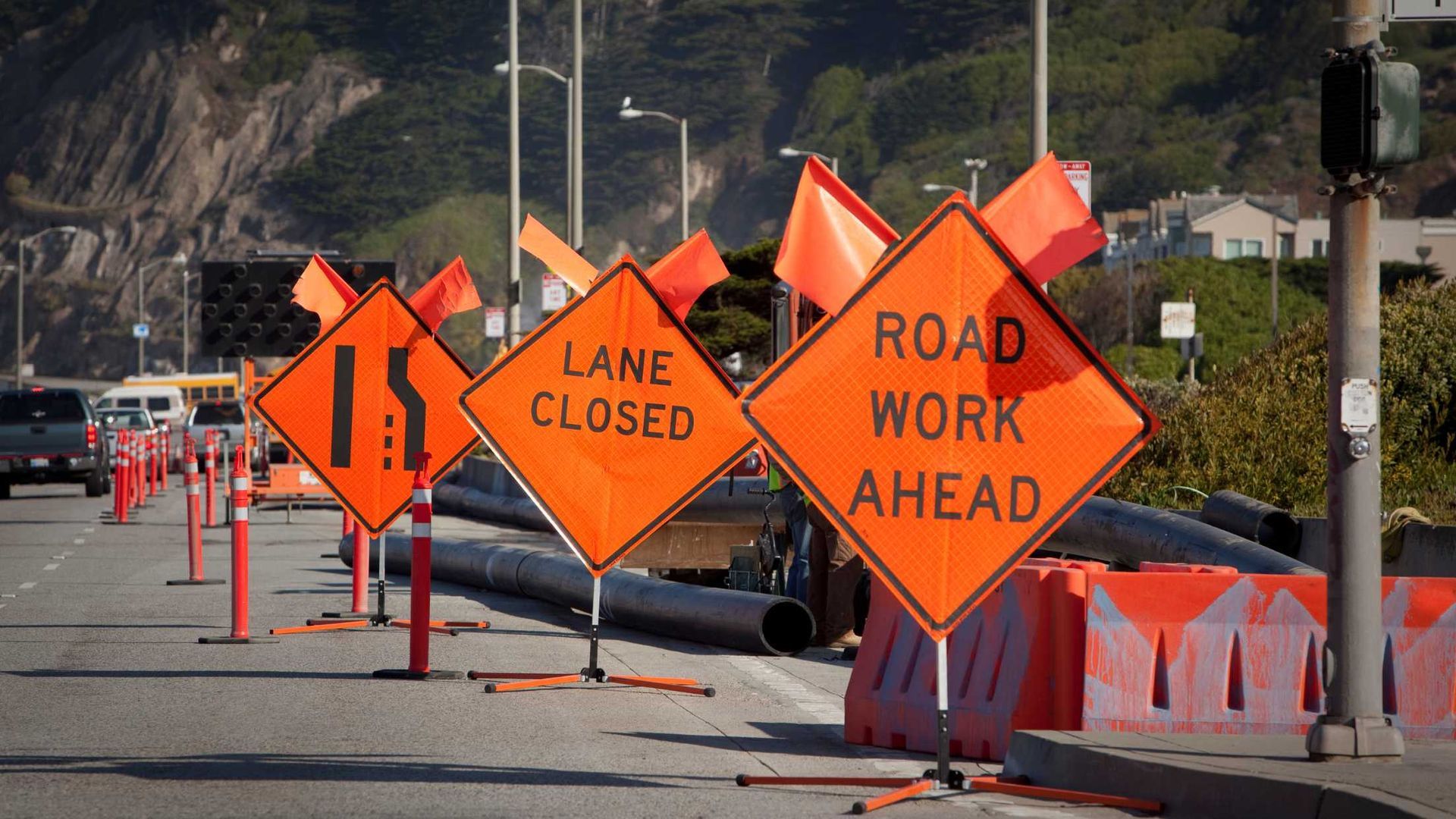 A row of orange signs that say lane closed and road work ahead