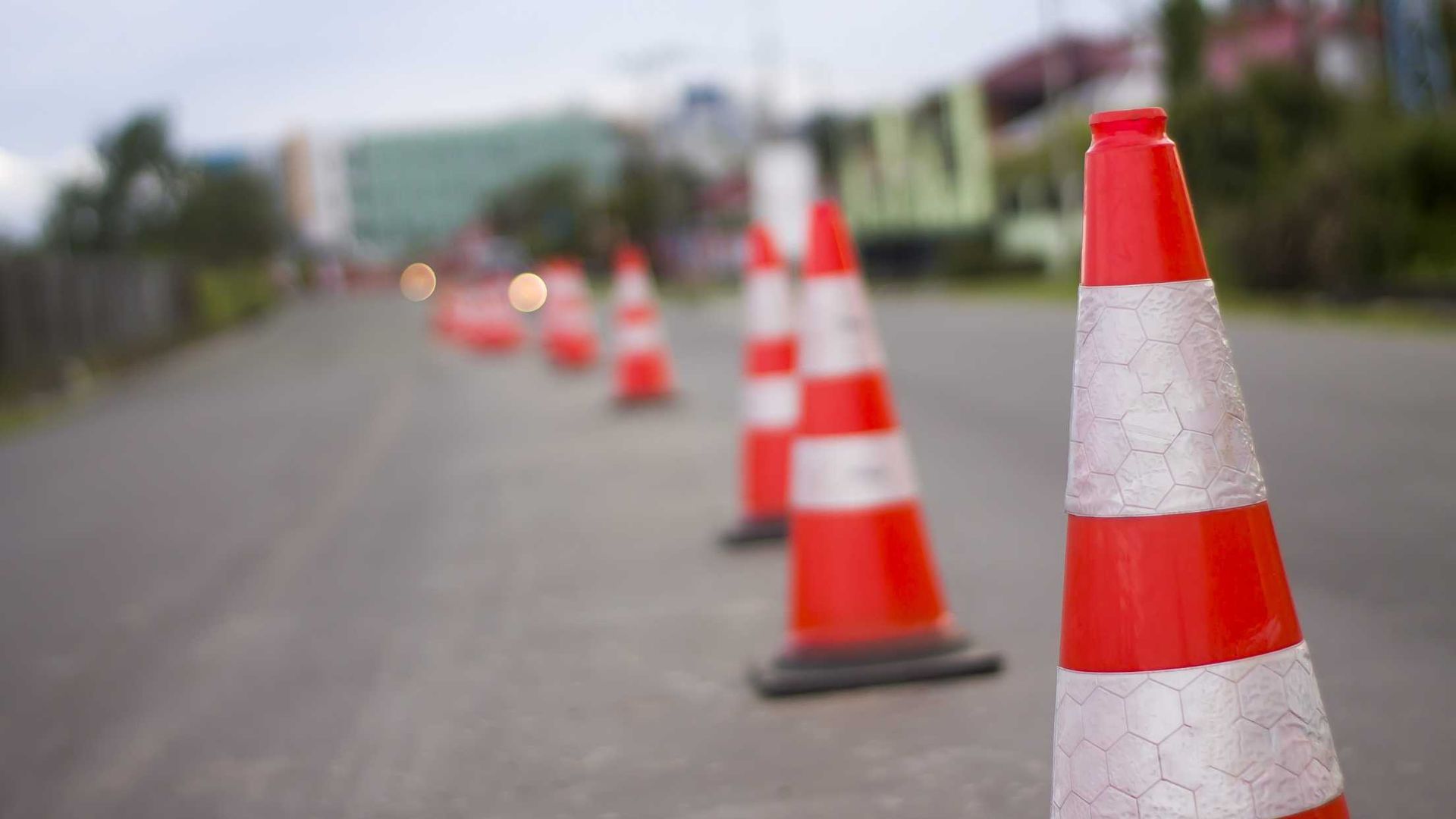 A row of red and white traffic cones on the side of a road.