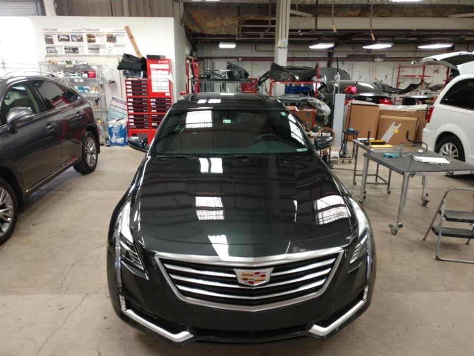 A black cadillac is parked in a garage with other cars