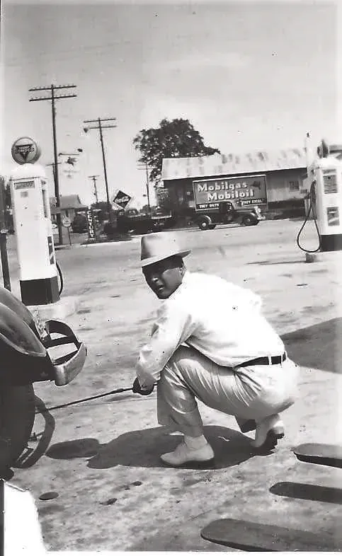A black and white photo of a man at a gas station