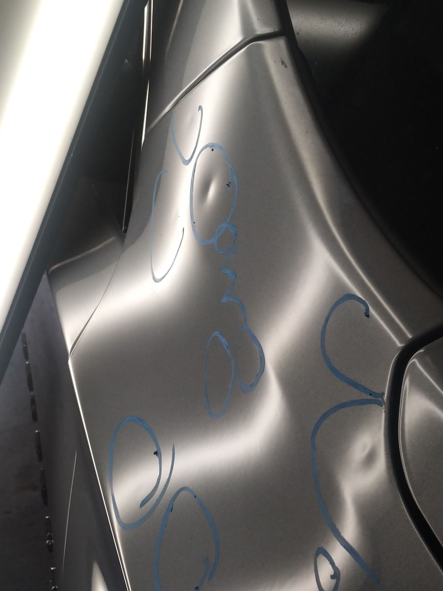 A silver car with a few dents on it