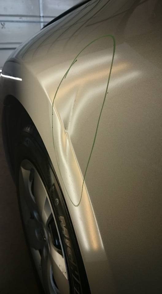 A close up of a car 's fender with a dent in it.