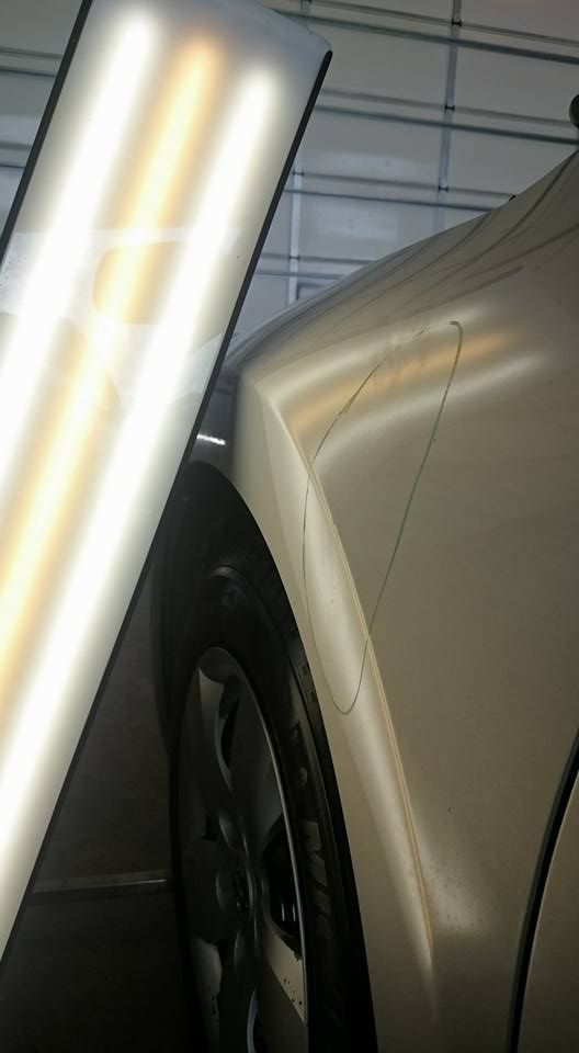 A close up of a car 's fender with a light shining on it
