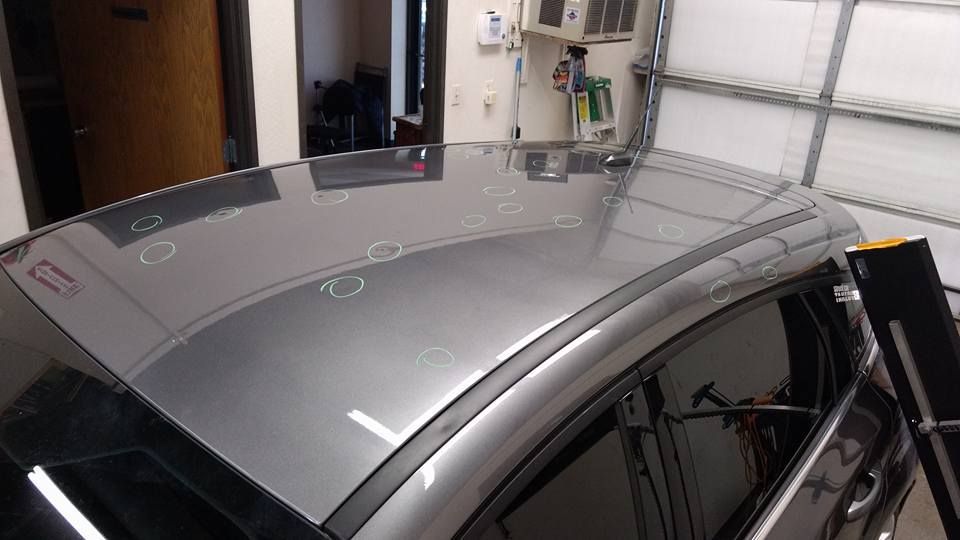 The roof of a car with a lot of dents on it is in a garage.