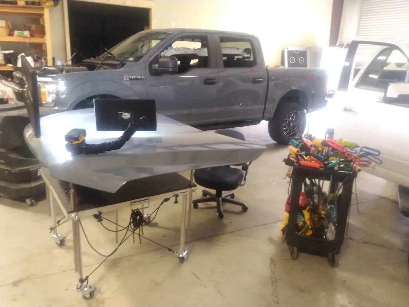 A truck is parked in a garage next to a table with tools on it.