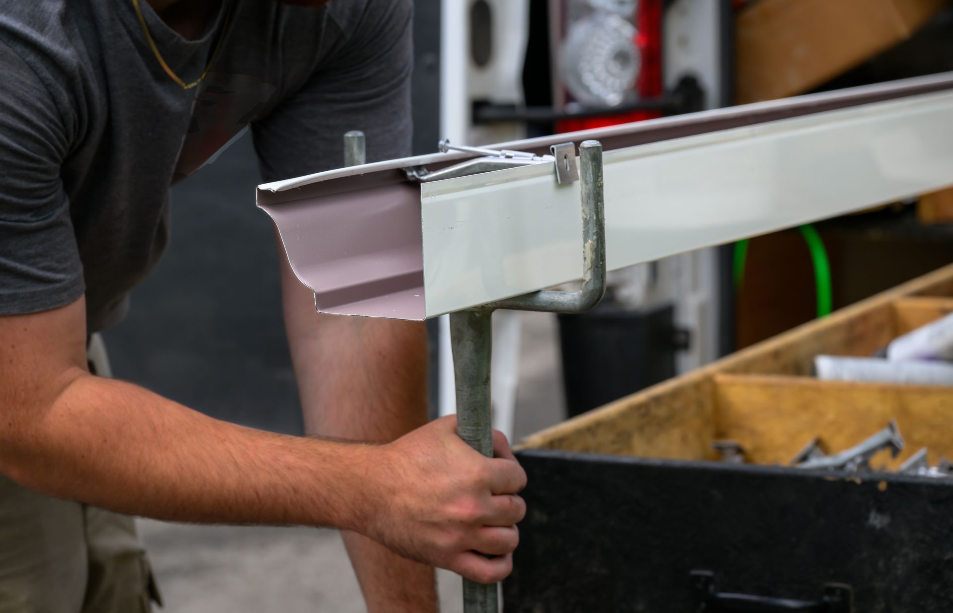 Person adjusting a white metal rail on a workbench in a workshop