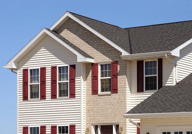 Suburban house exterior with beige siding, red shutters, and dark shingled roof