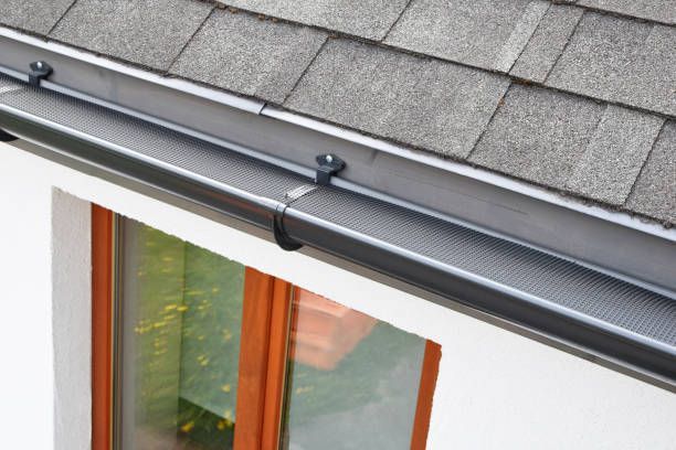Roof gutter and downspout above a window on a white house exterior