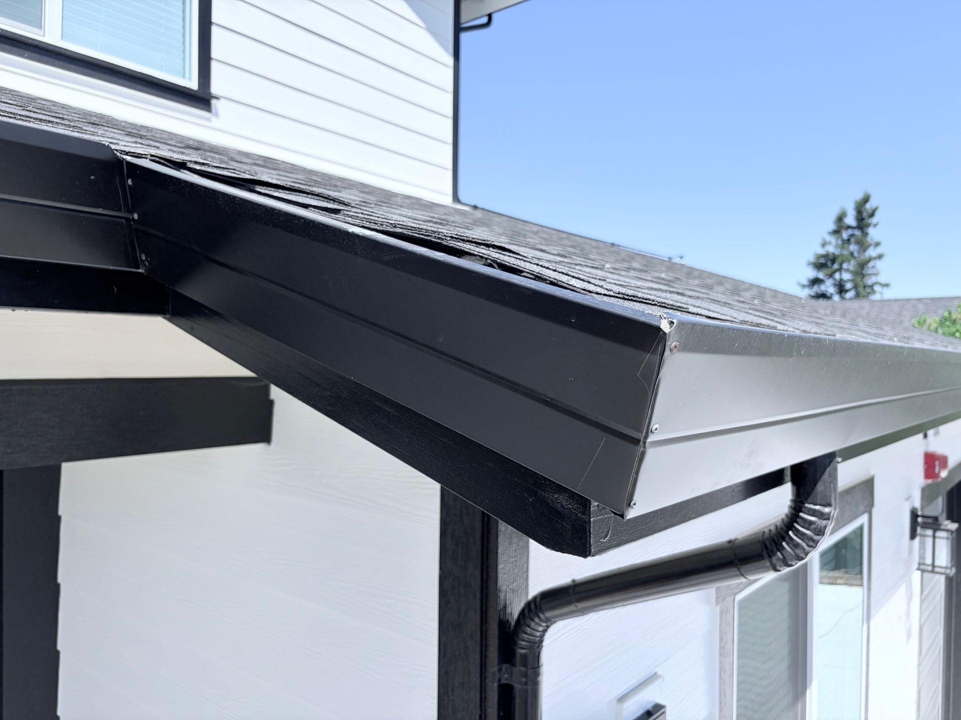 Durable black metal gutters and downspout system set up by a professional gutter contractor.