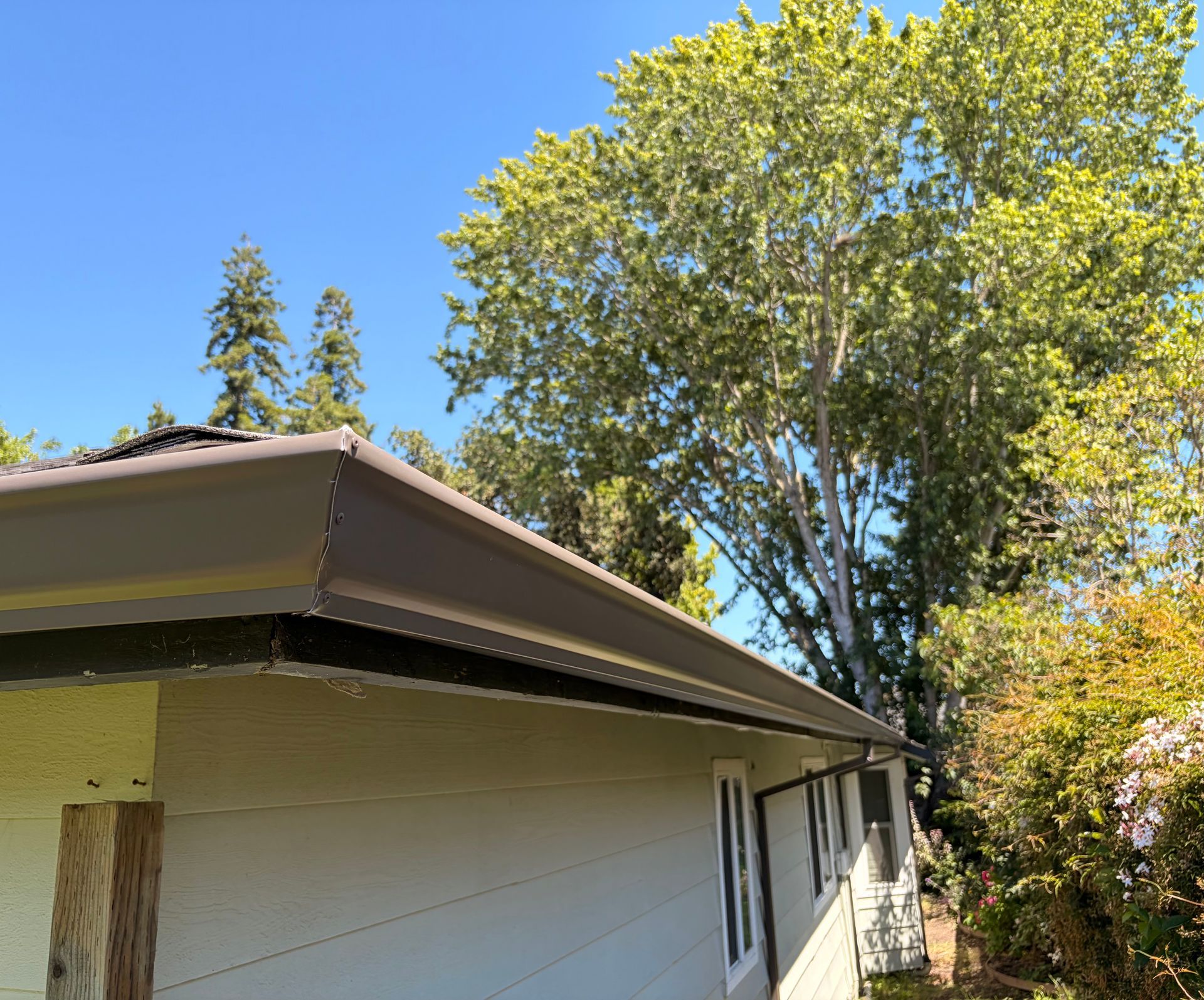 Brown seamless rain gutter installed along the roof edge of a residential home.