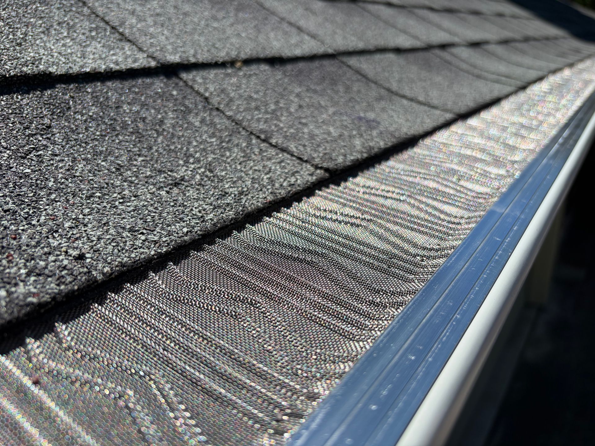 Close-up of a gray shingle roof with a blue metal edge and textured granules Close-up of a gray shingle roof with a blue metal edge and textured granules