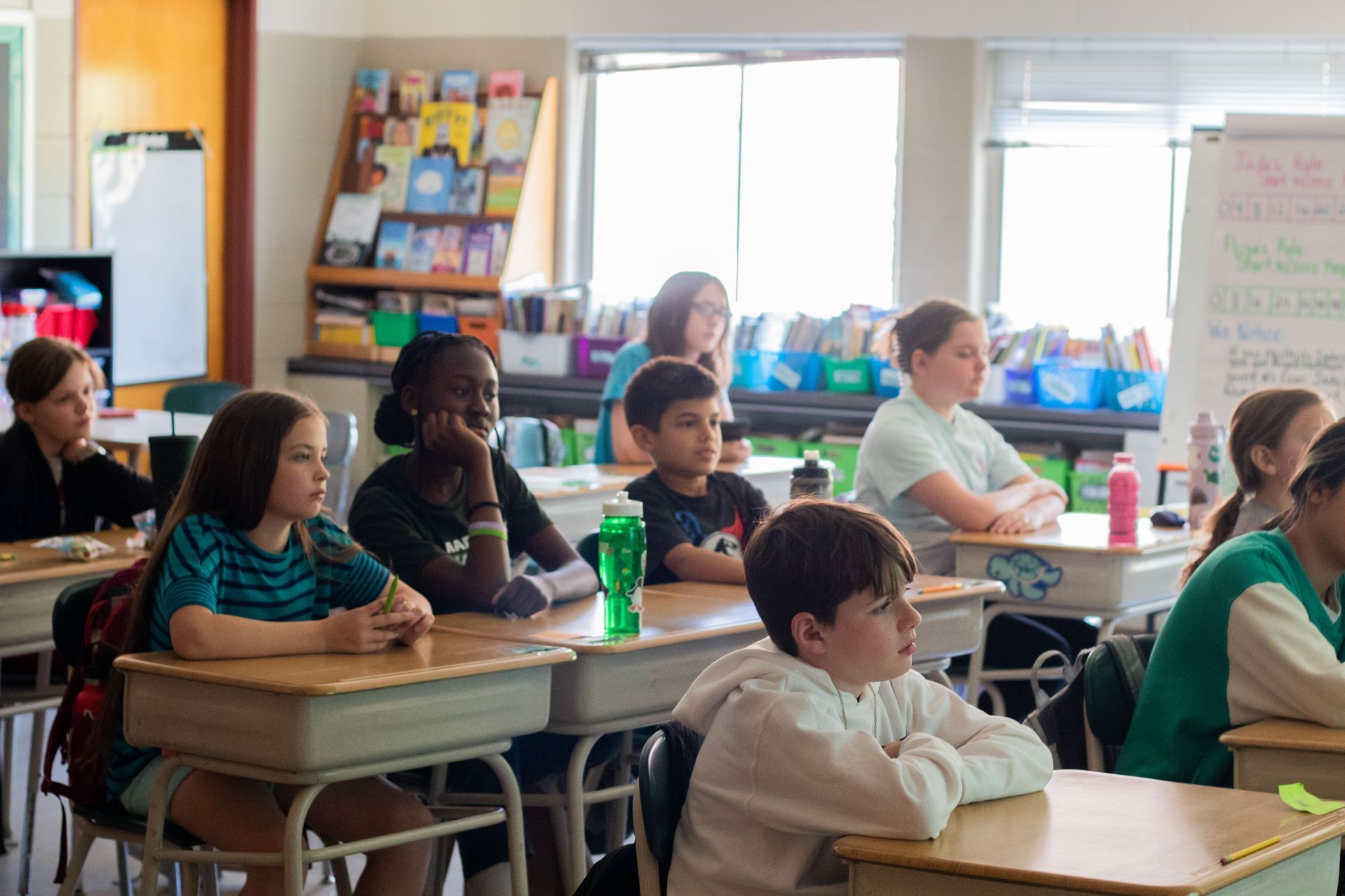 Children seated at desks, looking forward in a classroom.