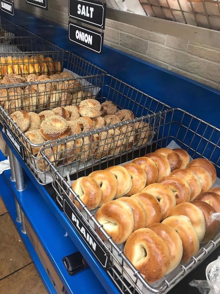 Bakery display with trays of assorted donuts and bagels under signs for salt and onion
