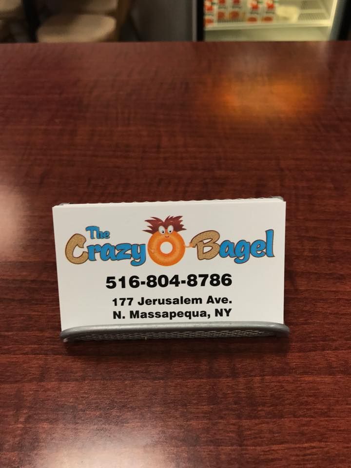 Business card for The Crazy Bagel with phone number and Massapequa, NY address on a wooden table.