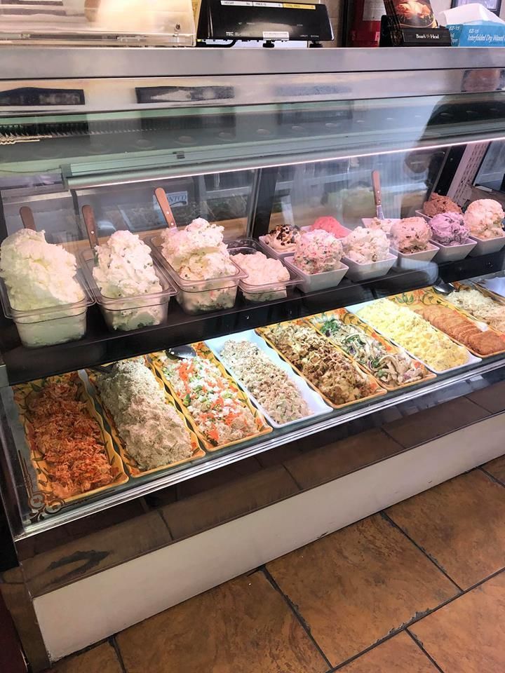 Deli counter with trays of pasta and salad in a glass display case.