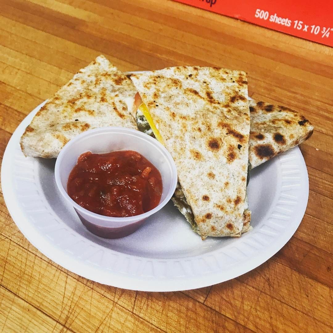 Quesadilla slices with salsa on a white plate atop a wooden table