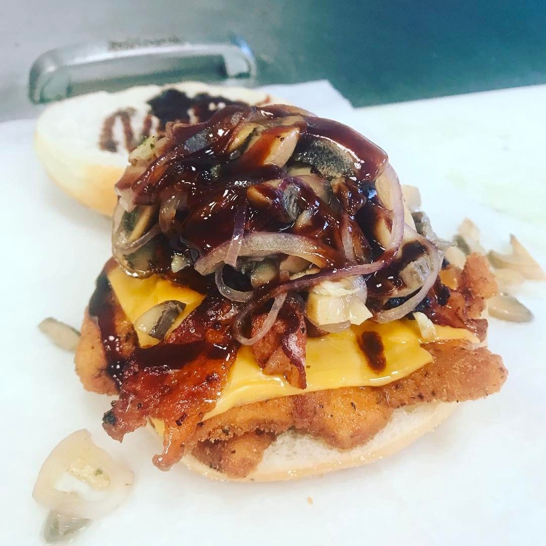Close-up of a cheeseburger topped with caramelized onions and dark sauce on a white plate