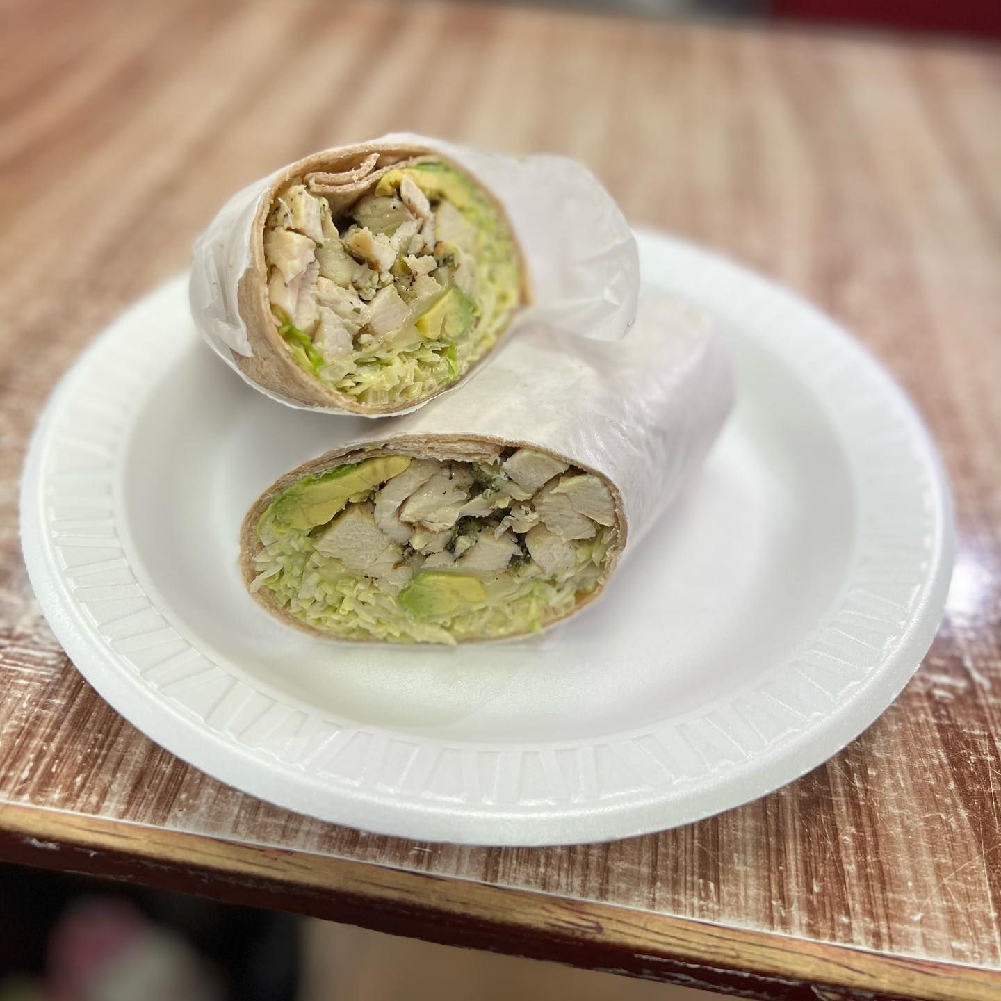 Cut chicken wrap halves on a white plate on a wooden table