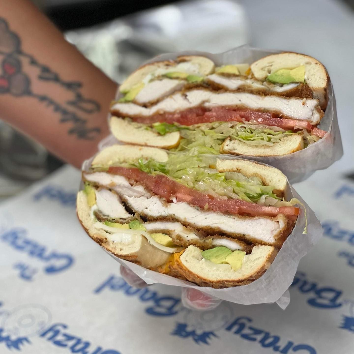 Cross-section of a deli sandwich with turkey, lettuce, tomato, and avocado on paper wrapping