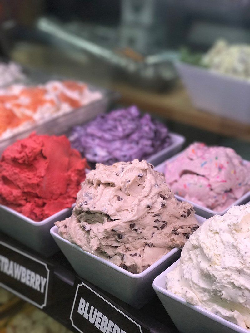 Assorted colorful gelato scoops in display trays at an ice cream shop counter