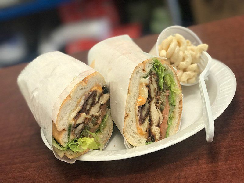 Two burrito halves on a plate with a side of macaroni salad and a fork on a table