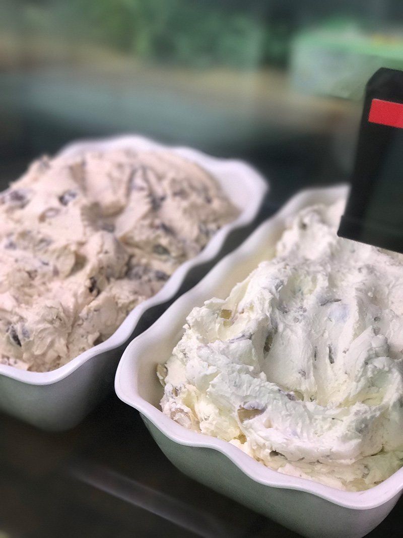 Two containers of creamy ice cream or gelato, one vanilla and one chocolate, in white trays