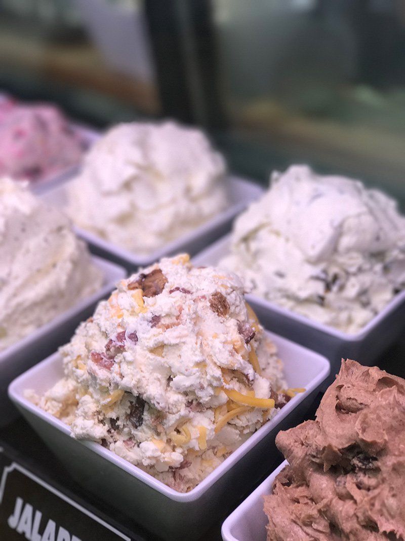 Assorted scoops of ice cream in square cups at a display case