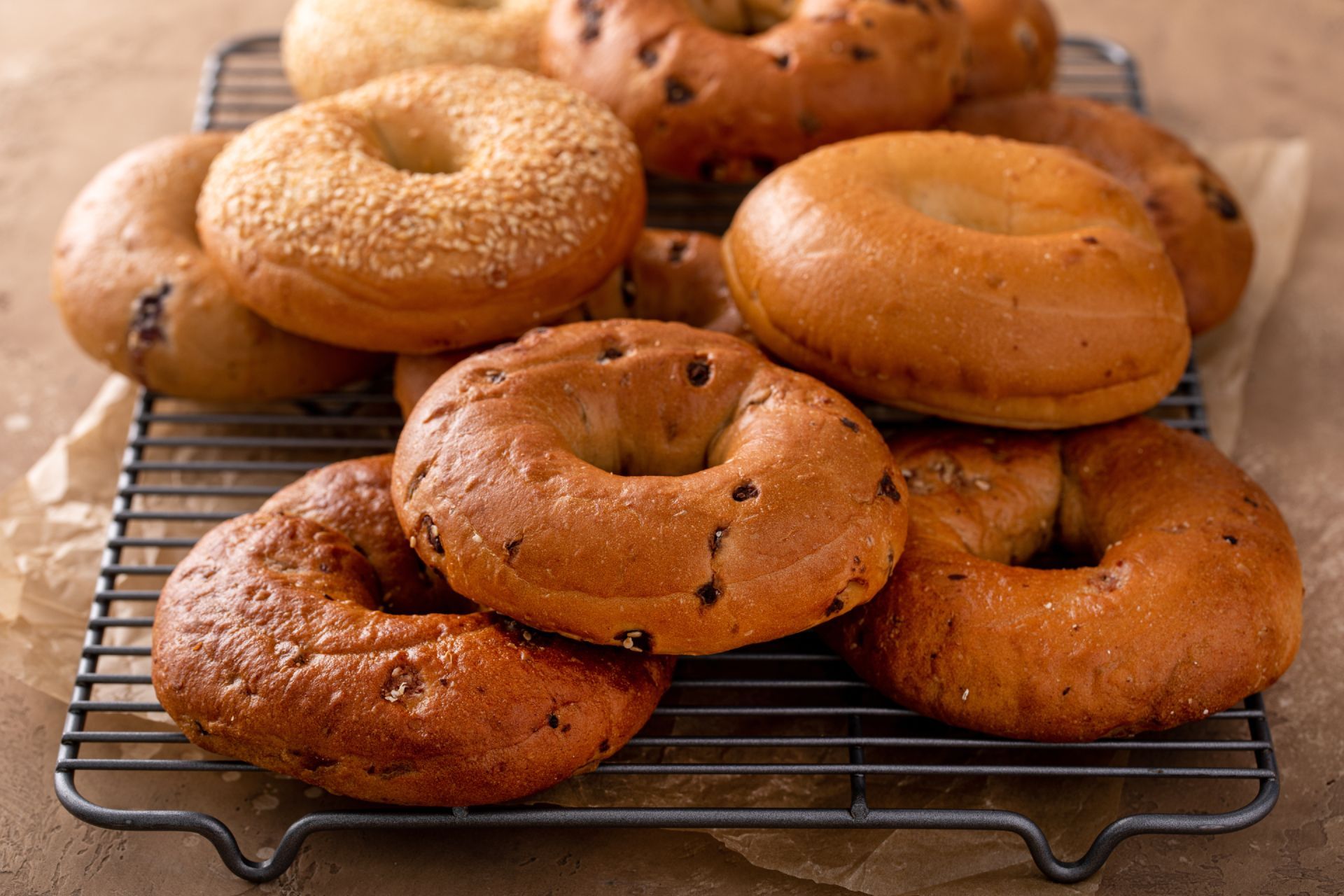 Assorted bagels cooling on a wire rack, with sesame and plain varieties.