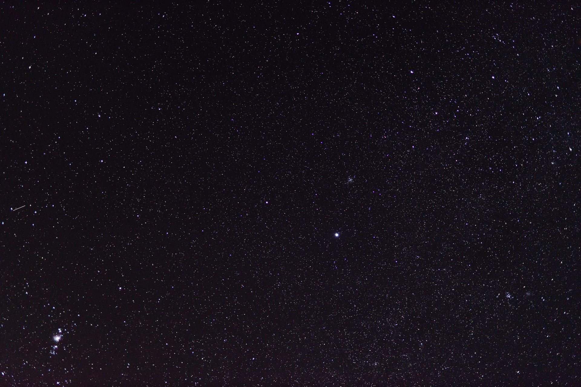 Star-filled night sky with a bright central star and a dark silhouette at the bottom left