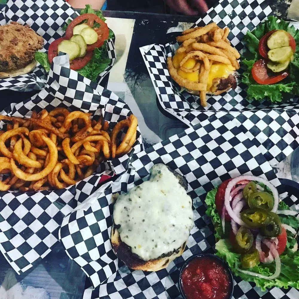 Assorted burgers and fries in black-and-white checkered baskets on a table