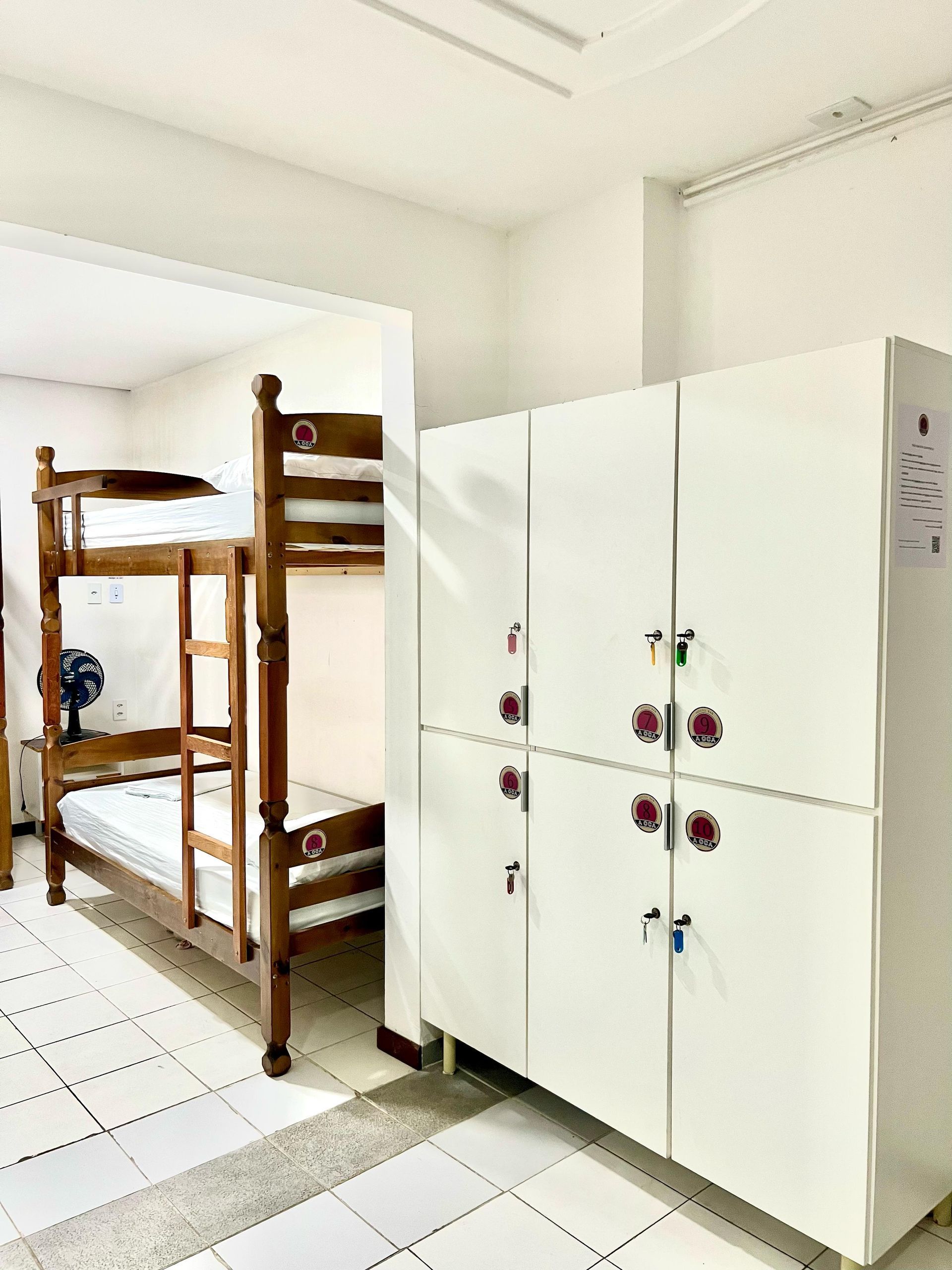 Quarto de dormitório com beliches à esquerda e armários brancos à direita.
