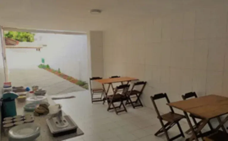Pequena área de jantar ao ar livre com mesas e cadeiras dobráveis ​​ao longo de uma parede revestida de azulejos.