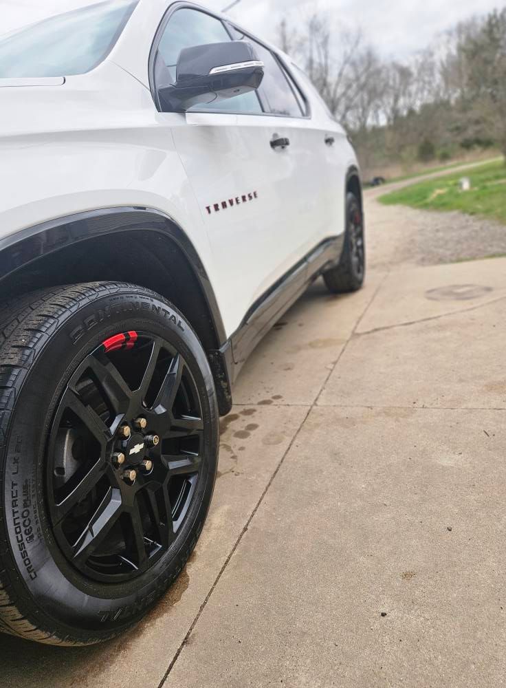 White Chevrolet Traverse SUV with black wheels on a concrete surface. 