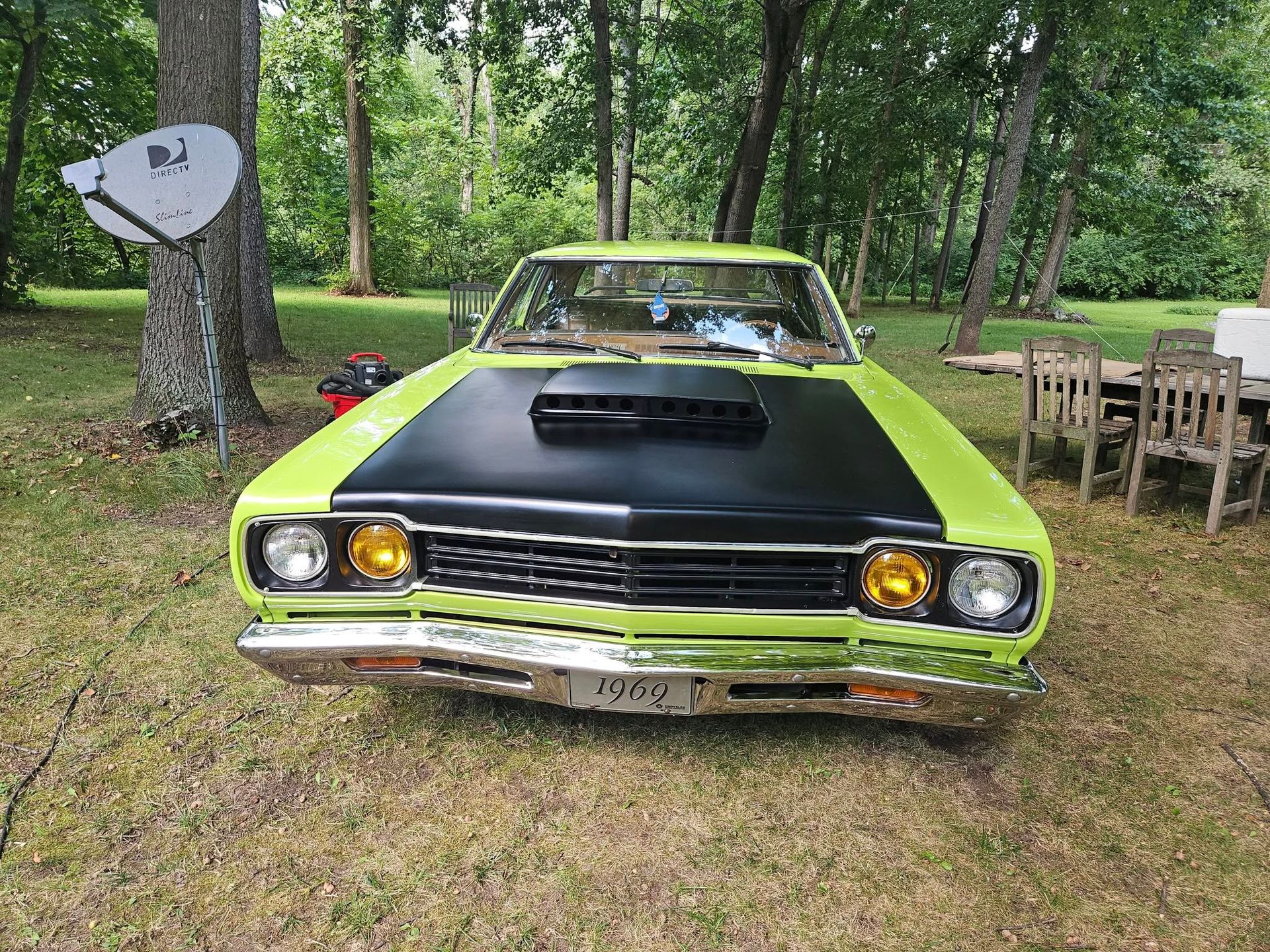 Lime green and black vintage muscle car parked on grass, daytime.