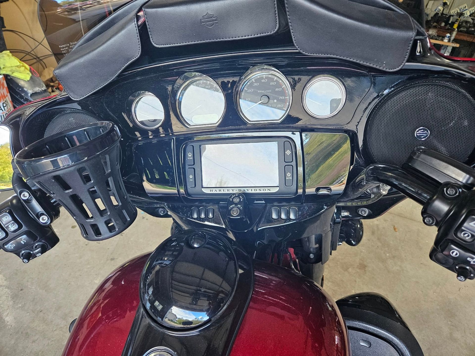 Close-up of a black motorcycle dashboard with gauges, a GPS, and cup holder. Red gas tank is visible.