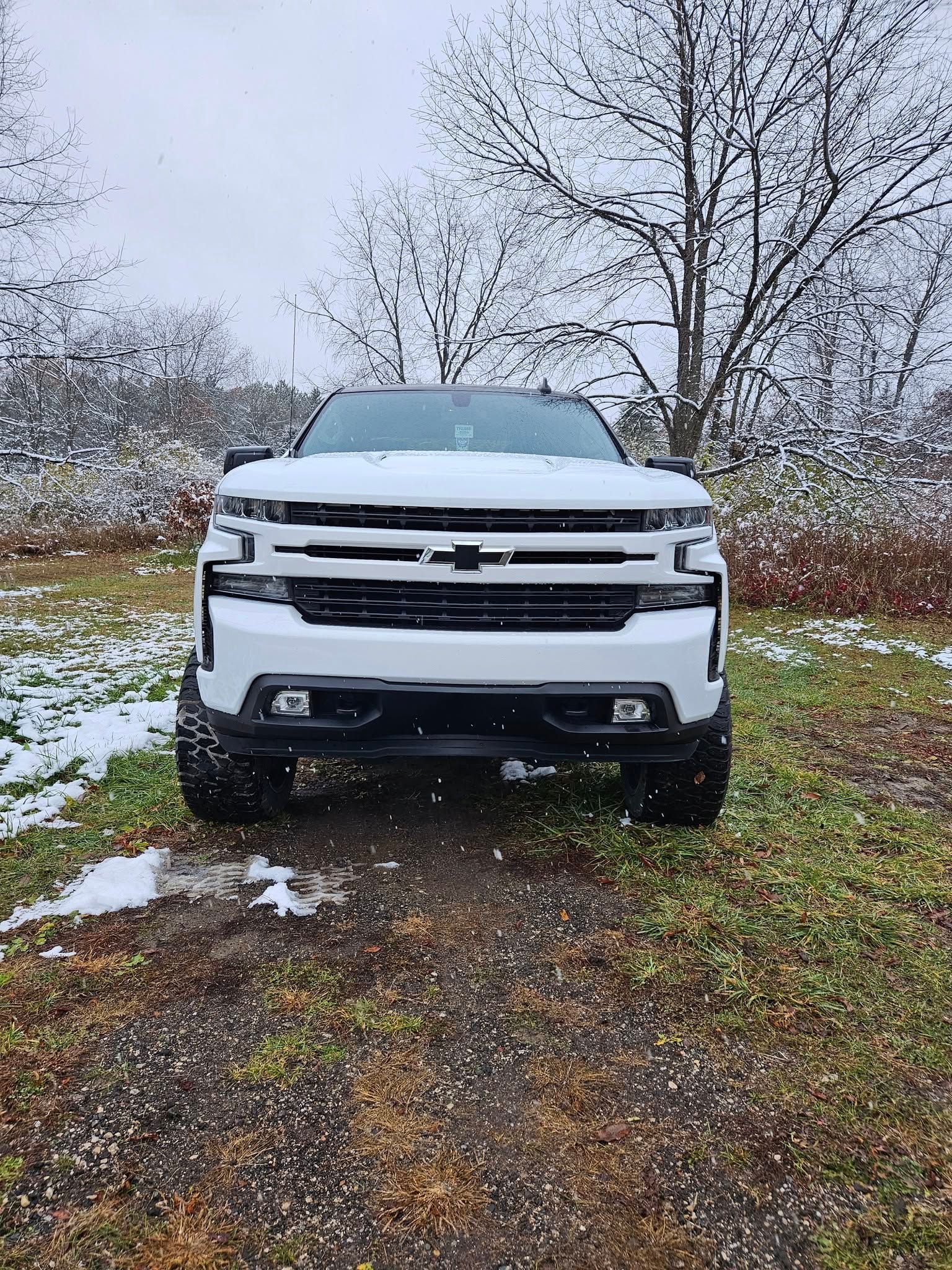 White Chevrolet pickup truck in a snowy field, facing the camera.