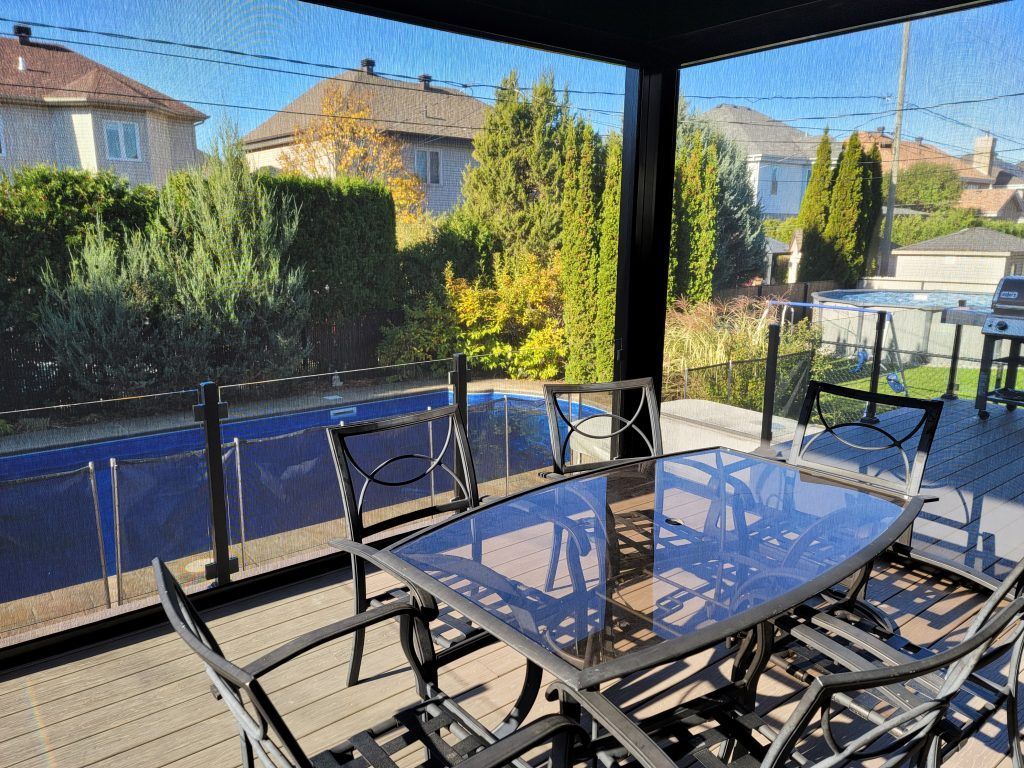 Un patio avec une table et des chaises et une piscine en arrière-plan.