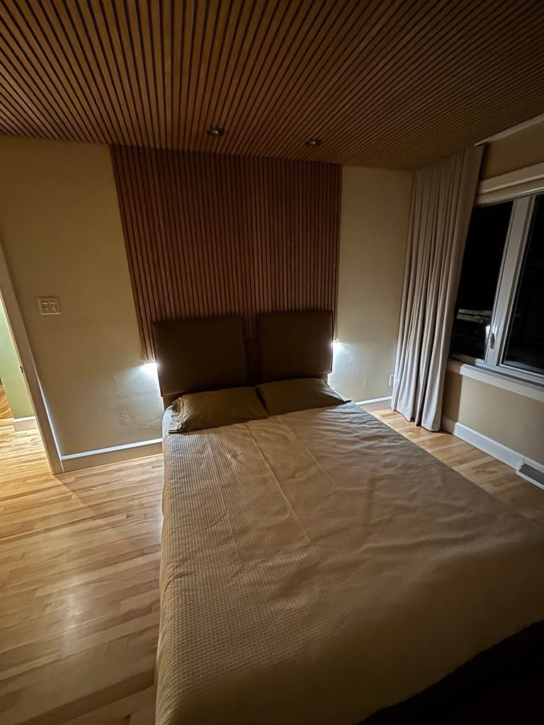 Une chambre avec un lit, une fenêtre et un plafond en bois.