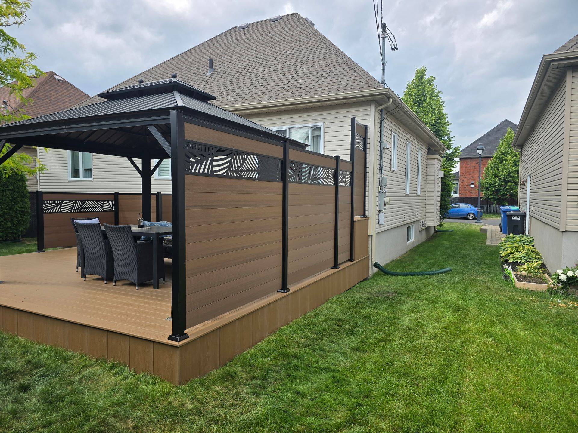 Une maison avec une terrasse en bois et un gazebo dans l'arrière-cour.