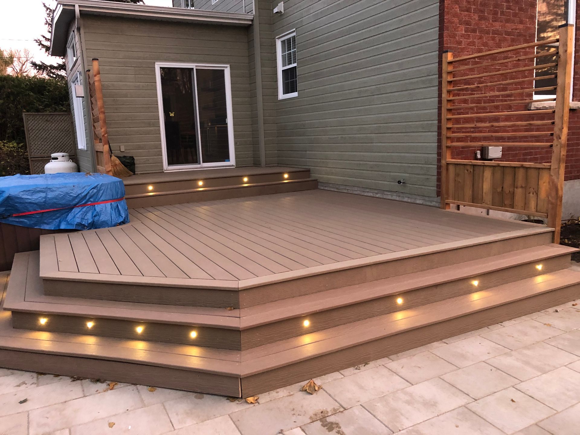 Une terrasse en bois avec des escaliers et des lumières devant une maison.
