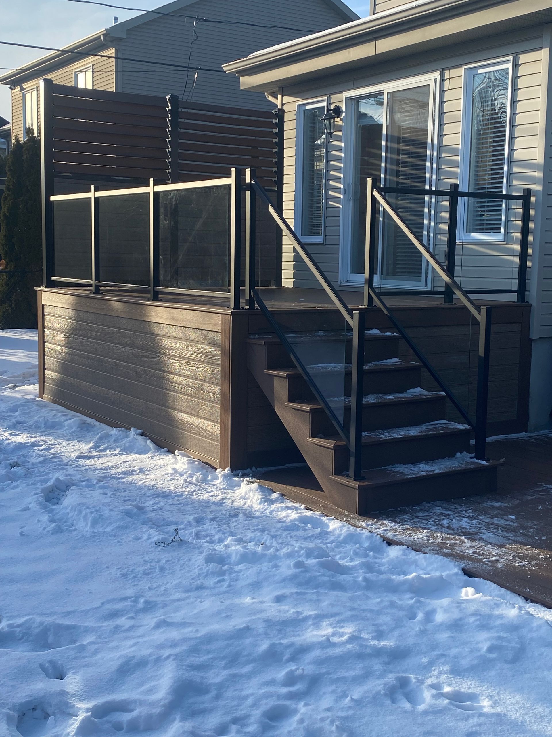 Une maison avec une terrasse et des escaliers dans la neige