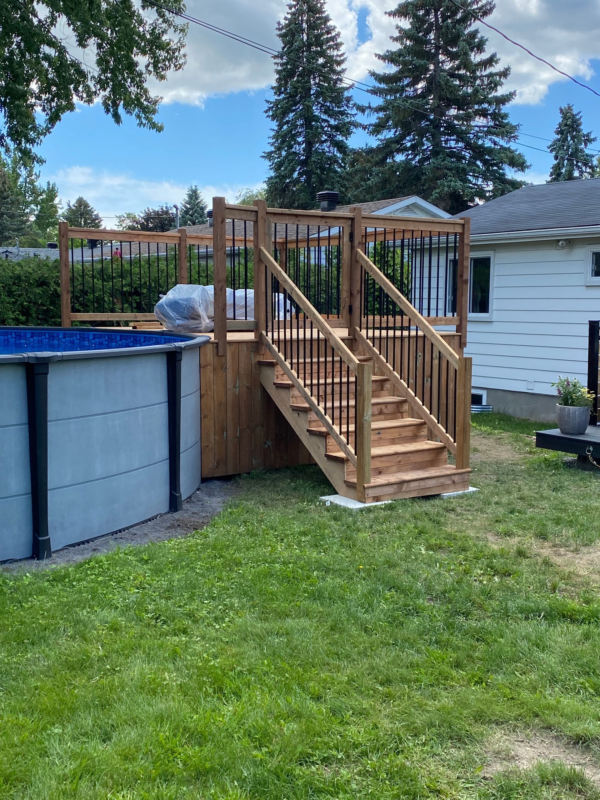 Une terrasse en bois avec des escaliers et une piscine dans l'arrière-cour d'une maison.