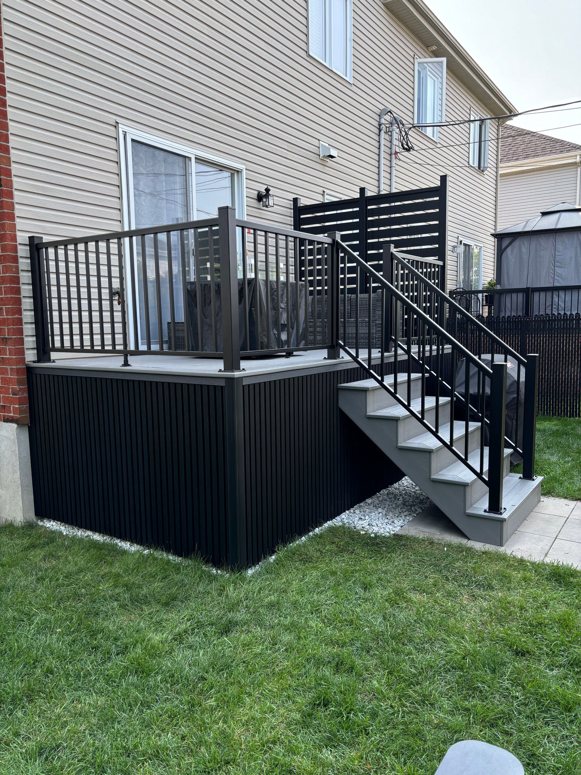 Une terrasse avec des escaliers qui y mènent se trouve dans l'arrière-cour d'une maison.