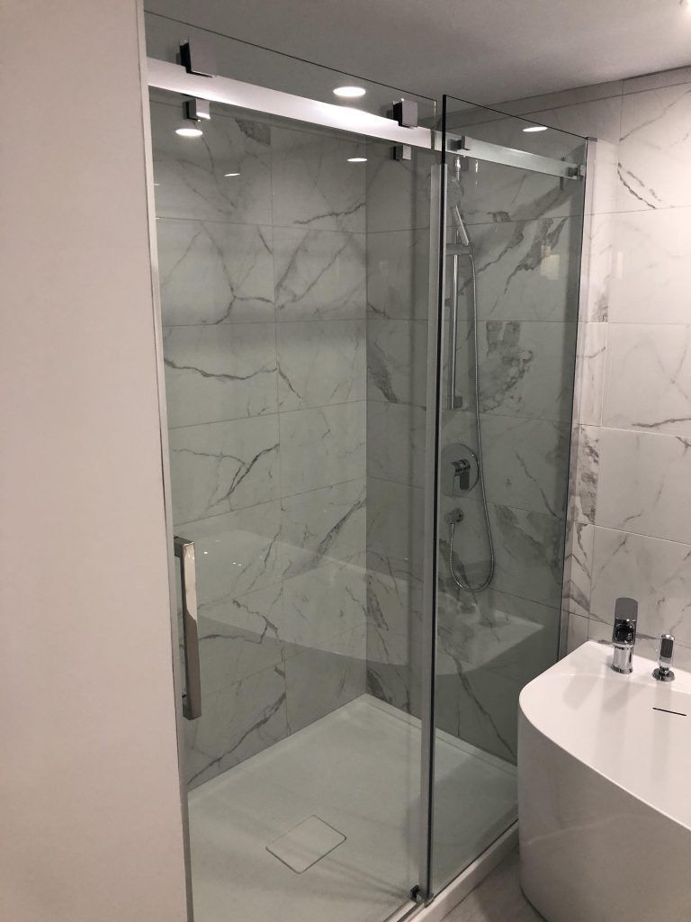 Une salle de bain avec une porte de douche coulissante en verre et une baignoire.