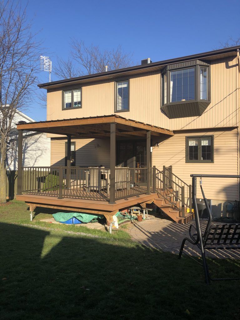 L'arrière d'une maison avec une grande terrasse et des escaliers.