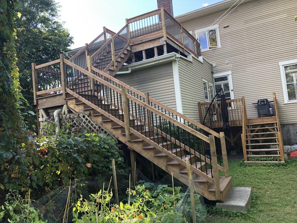 Une terrasse en bois avec des escaliers qui y mènent et une maison en arrière-plan.