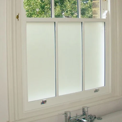 Un baño con una puerta de ducha corrediza de vidrio con un delfín y palmeras en ella.