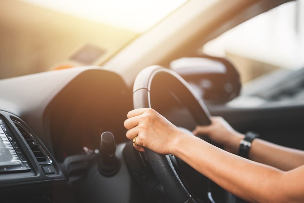 A Woman Is Driving A Car With Her Hands On The Steering Wheel — JA Toft & Co In Bundaberg Central, QLD
